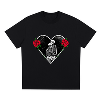 Black T-shirt featuring a heart-shaped graphic with two skeletons embracing under a crescent moon. The heart is adorned with red roses and green leaves.